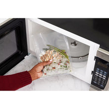 Vacuum storage bag with prepared food inside, being sealed in a vacuum sealer
