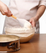 Silicone ladle with bamboo handle scooping batter from a bowl