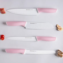 Assorted stainless kitchen knives with pink handles, arranged on a light surface