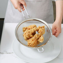 Fine mesh stainless steel strainer holding cooked food over a plate