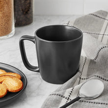 Matte black stoneware mug with handle on checkered table setting