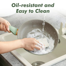 Green nonstick skillet being washed with soapy water and sponge