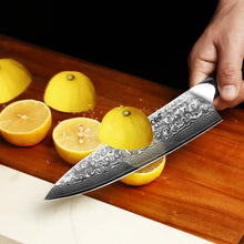 Damascus chef knife with black resin handle slicing through lemons and citrus