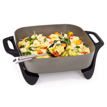 Ceramic electric skillet holding chicken and vegetables with black side handles