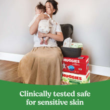 Baby wipes box on floor with caregiver holding an infant on couch