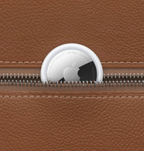 Apple AirTag tracker clipped to a tan leather zipper pouch