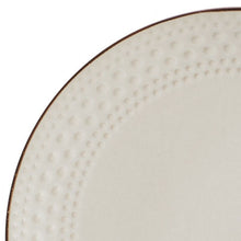 Beige stoneware plate close-up with embossed dot texture and brown rim