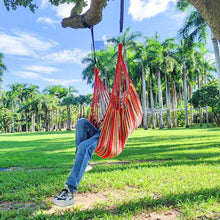 Hanging hammock chair with red and multicolor striped fabric, suspended by ropes