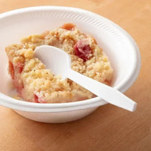 White plastic spoon resting on bowl of food, disposable serving utensil