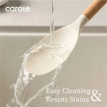 White silicone cooking spatula with light wood handle pouring batter from a bowl