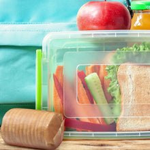 Clear lunch container with crackers, cheese slices, and vegetable toppings