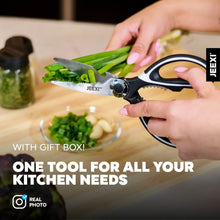 Kitchen scissors with black and red handles trimming green herbs