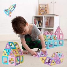 Child playing with magnetic building blocks set in pastel house and star shapes
