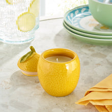Yellow ceramic lemon fruit candle with lit single wick in a glossy ceramic cup