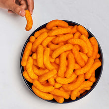 Bowl of orange puff snacks with a hand holding one