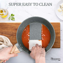 Gray speckled saucepan with glass lid, held steady by two hands