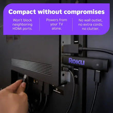 Roku streaming stick plugged into TV HDMI port with hand inserting cable