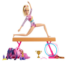Gymnast doll posing on balance beam with pink bag, trophy, and small accessories