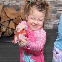 Child playing with orange dinosaur toy at a blue plastic dino water table