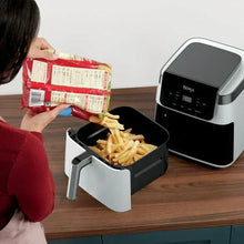 Ninja air fryer with open basket as fries are added, white drawer-style basket