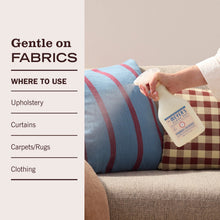 Fabric freshener bottle applying mist to upholstered cushions, gentle use.