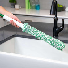 Twist mop with green handle and green-and-white yarn head laid across sink