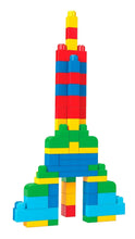 Colorful plastic block rocket tower with yellow top, red stripe, blue bands, and green base