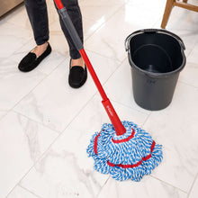 Microfiber mop on red handle with blue-white braided head and red stitched edge near bucket