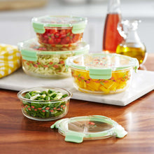Glass food storage containers with green lids and floral print, filled with produce