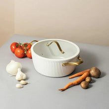 White ribbed Dutch oven with gold handles and domed lid