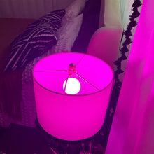 Color-changing smart LED bulb glowing bright purple inside a small lamp shade