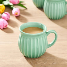 Green stoneware mug with ridged pattern and handle, filled with light liquid