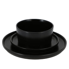 Black stoneware dinner plate with stacked bowls, glossy finish