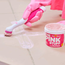 Pink Stuff cleaning paste tub next to a scrub brush on a sink