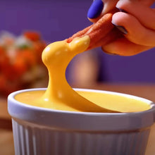 Spicy yellow cheese dip being poured into a white bowl