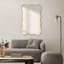 Large wavy-edge wall mirror with gold frame against a wall