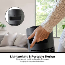 Black tower fan with top control panel and hand pressing a button