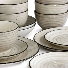 Cream stoneware dinnerware set, close-up of stacked bowls and plates with swirl rims