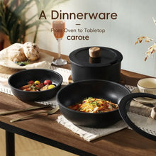 Black nonstick skillet and pot set on a wooden table with lids and served food