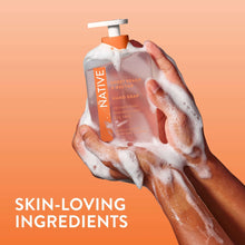 Native hand soap dispensing with foamy lather on hands, orange pump and label visible
