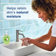 Liquid hand soap pump bottle beside foamy hands washing at sink
