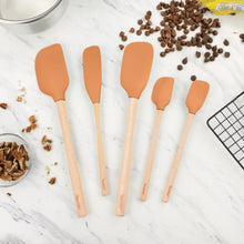 Set of 5 apricot silicone spatulas with light wood handles on countertop