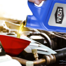 Motor oil being poured from a blue jug into an engine bay