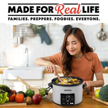 Programmable slow cooker on a kitchen table with lid open and food inside, touchscreen visible