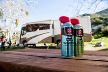 Two RVcare lubricant cans with red caps on an outdoor surface