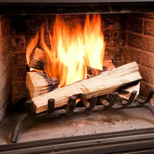 Open fireplace with flames burning over stacked fire starter logs on a metal grate.
