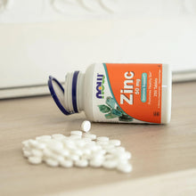 Zinc 50 mg supplement bottle with scattered white tablets on a surface