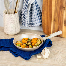Taupe speckled fry pan with gold handle holding roasted vegetables