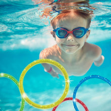 Child holding an orange sparkly pool dive ring with blue and green rings nearby