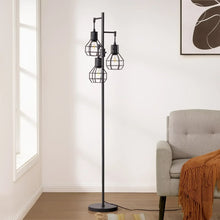 Black standing floor lamp with four wire cage shades beside a living room sofa